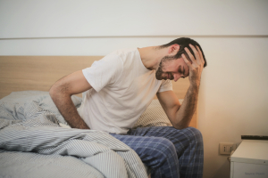 Uomo seduto sul letto con la mano sulla testa